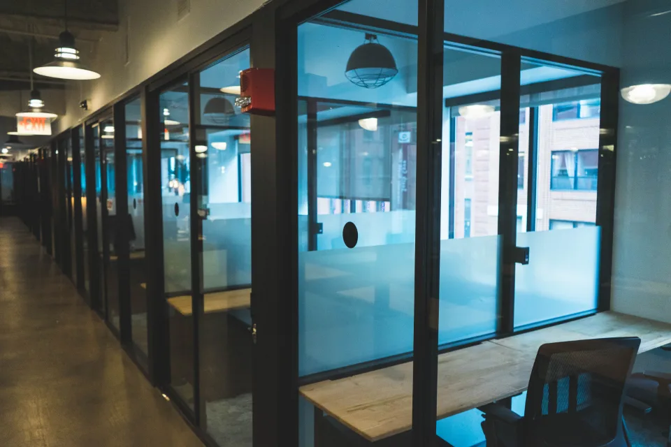 Corridor of glass-walled meeting rooms lit blue